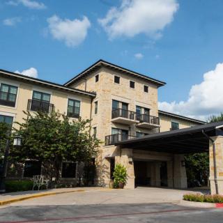 A modern hotel building with stone exterior under a blue sky with clouds.