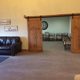 A cozy lobby featuring a leather sofa and wooden sliding doors leading to an empty room with chairs.