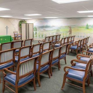 An empty room with neatly arranged wooden chairs and a mural on the wall.
