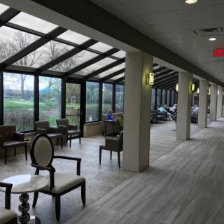 A spacious interior seating area with large windows allowing natural light to illuminate the space, furnished with chairs and tables.