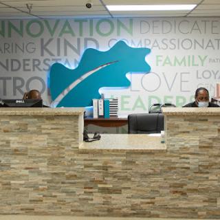 A welcoming reception area with two staff members behind the front desk, featuring a modern design and inspirational wall words.