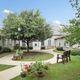 A peaceful garden courtyard with a walkway, benches, and lush greenery.