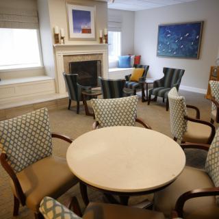 A cozy living room with a round table, upholstered chairs, and a fireplace.