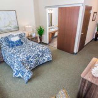 A cozy bedroom with a blue patterned bedspread and simple decor.