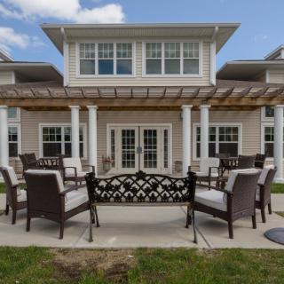 A spacious patio with outdoor seating in front of a large house.