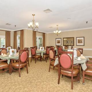 An elegant dining room with neatly arranged tables and chairs, adorned with chandeliers.