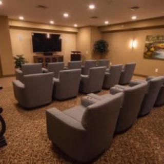 A cozy home theater setup featuring multiple armchairs facing a large screen.