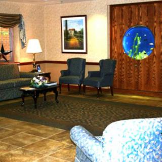 A cozy living room features sofas, chairs, a coffee table, and decorative artwork.