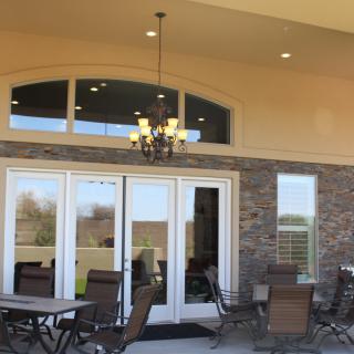 A cozy patio area with outdoor seating, featuring glass doors and a stone wall.