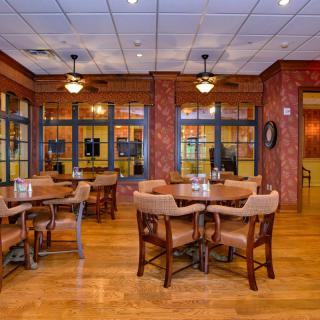Cozy restaurant interior with wooden flooring and neatly arranged tables and chairs.