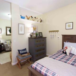 A cozy bedroom with plaid bedding, decorated with various home decor items and furniture.