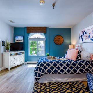 A brightly decorated bedroom with twin beds, featuring blue accents and a TV.