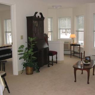 A cozy living room with a piano, armchair, and natural lighting.
