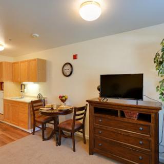 A cozy apartment interior featuring a small kitchen, dining area, and living space.