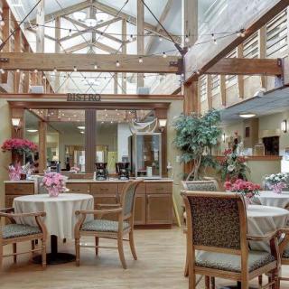 A bright and welcoming restaurant interior with wooden decor, featuring tables and chairs arranged neatly under natural lighting.