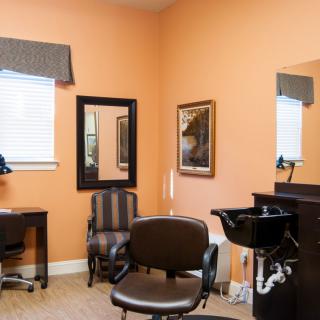 A cozy hair salon interior with chairs, mirrors, and a washing sink.