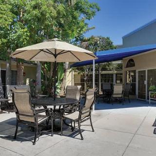 A sunny patio area with a table, chairs, and an umbrella for shade.