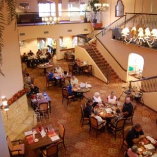 A cozy restaurant interior with diners seated at tables and a staircase leading to an upper level.