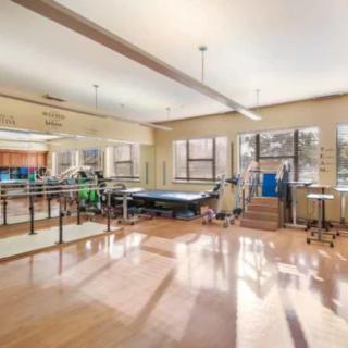 A spacious rehabilitation clinic with exercise equipment and therapy areas.