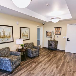 A cozy lobby area with chairs, paintings, and wood flooring.