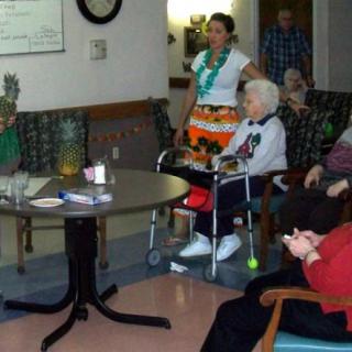 A group of elderly people sitting in a nursing home, participating in an indoor activity.