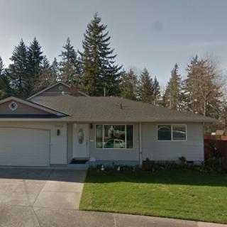 A suburban single-story house with a garage and a front yard, surrounded by trees.