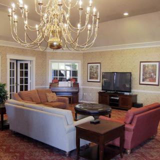A cozy living room featuring a large chandelier, comfortable seating, and a television.