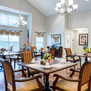 An elegant dining room with multiple tables and chairs, decorated with chandeliers and an American flag.