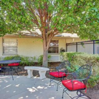 A cozy outdoor patio area with chairs and a table under a tree.