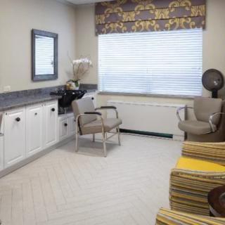 A cozy salon interior with chairs, a hair dryer, and a mirror by the window.