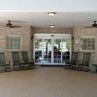 A covered porch area with multiple rocking chairs facing the entrance.