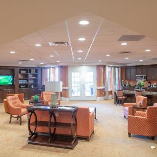 A spacious and well-lit living room with comfortable seating, a television, and a bookshelf.