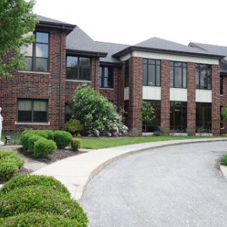 A modern brick building with landscaped surroundings and a curved driveway.