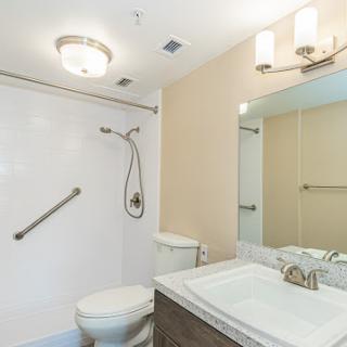 A modern bathroom featuring a shower, toilet, and sink with contemporary lighting.