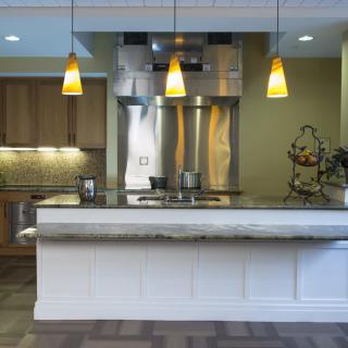 A modern kitchen interior with pendant lights and stainless steel appliances.