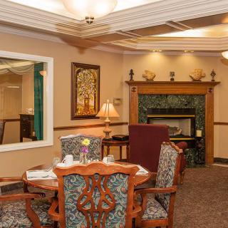 A cozy living room with a warm fireplace, ornate dining table, and traditional decor.