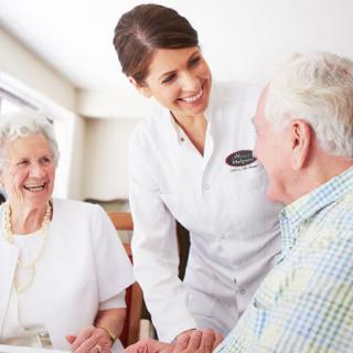 A nurse interacting with two senior individuals, providing attentive care and support.