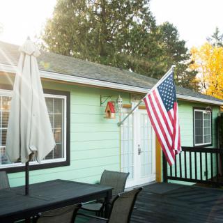 A cozy patio with outdoor furniture, featuring an American flag mounted on a mint-green house.