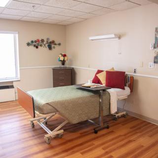 A clean and empty hospital room with a bed and minimal furnishings.