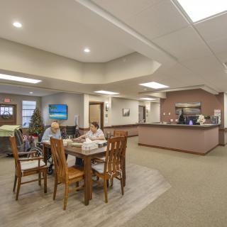 A welcoming lobby area with people seated around a table near the reception desk.