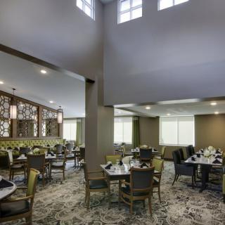 A spacious dining area with neatly arranged tables and chairs, featuring large windows and modern lighting.