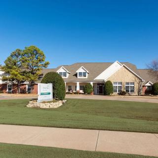 A suburban house with a well-maintained lawn and clear blue sky.
