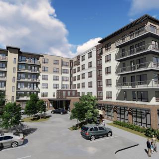 Modern residential apartment complex with a parking area in front.