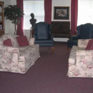 A cozy living room with floral sofas and elegant chairs.
