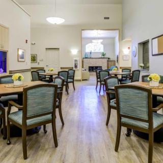 A spacious dining room with neatly arranged tables and chairs, featuring elegant lighting and decor.