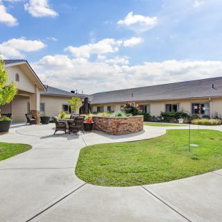A well-maintained courtyard with a seating area and surrounding buildings under a blue sky.