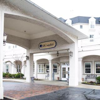 The front entrance of a white building with an awning and multiple windows.