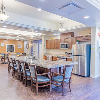 A spacious modern kitchen and dining area with a long table, multiple chairs, and stainless steel appliances.
