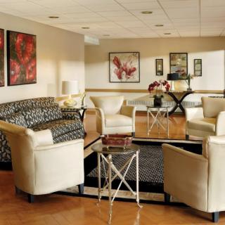 A contemporary living room featuring elegant armchairs, a patterned sofa, and modern artwork.