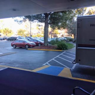 A view of a parking lot with several cars and trees in the background.